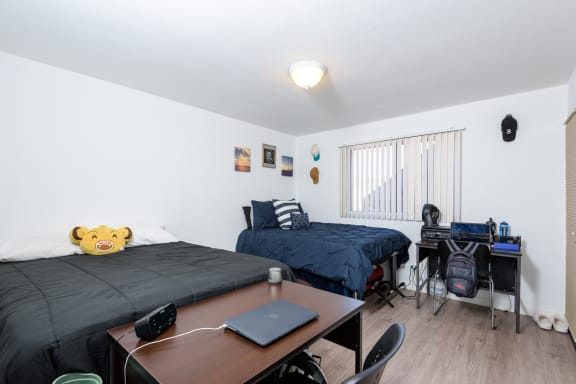 a bedroom with two beds and a desk and a window