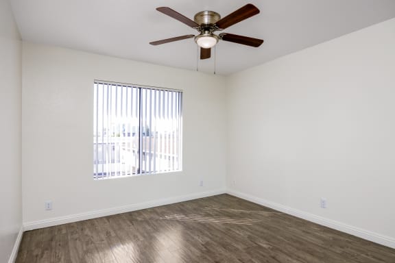 an empty room with a ceiling fan and a window