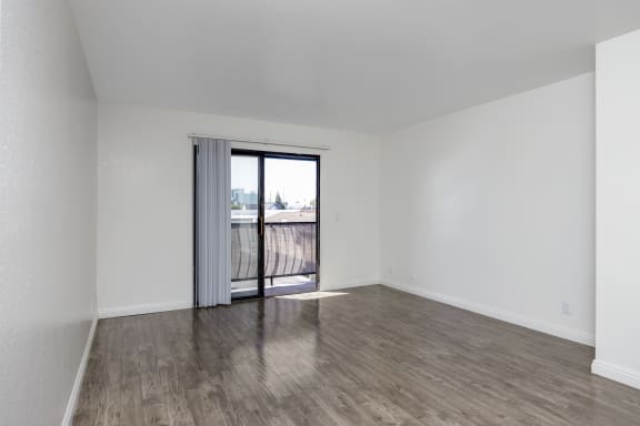 an empty living room with a sliding glass door to a balcony