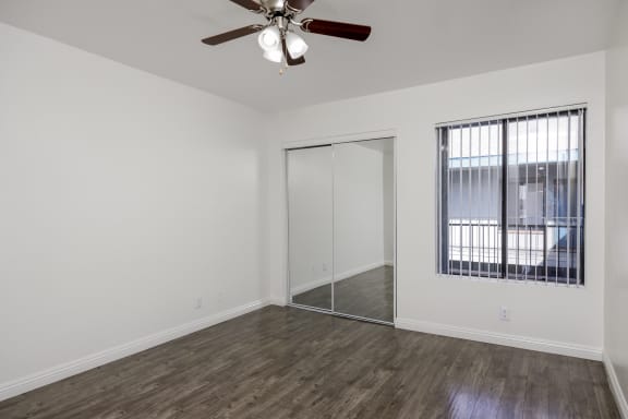 an empty living room with a ceiling fan and a window