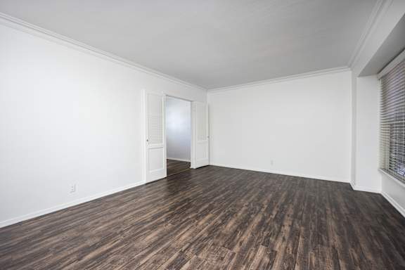 an empty living room with white walls and wood flooring