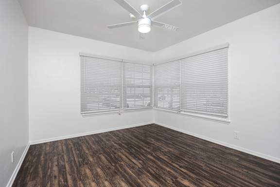 an empty living room with wood flooring and a ceiling fan