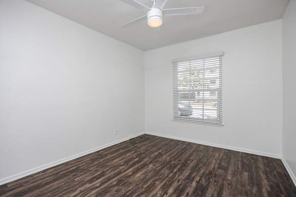 an empty room with wood flooring and a window