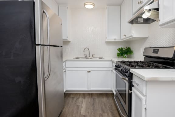 a white kitchen with stainless steel appliances and white cabinets