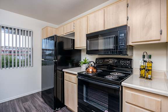 an apartment kitchen with black appliances and wood cabinets