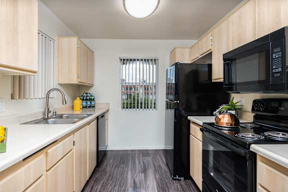 an apartment kitchen with black appliances and wooden cabinets