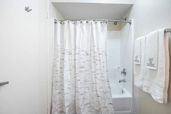 a bathroom with a shower curtain and a tub and towels