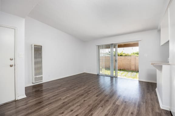 an empty living room with wood floors and a sliding glass door