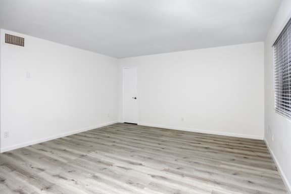 an empty room with white walls and wood floors