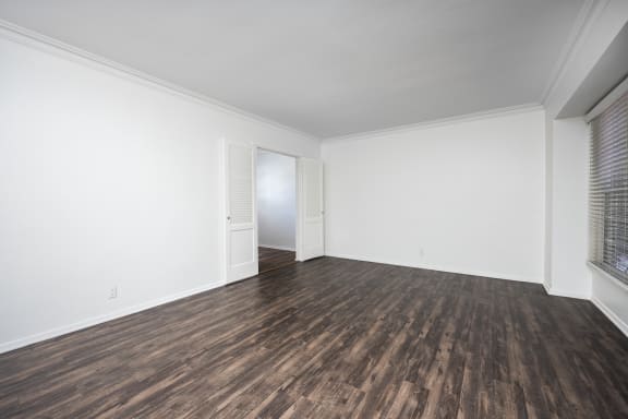an empty living room with white walls and wood flooring