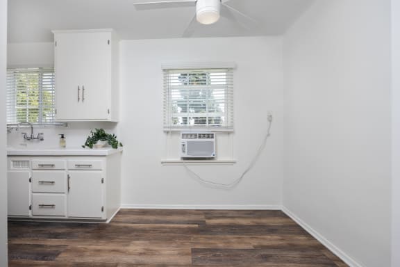 a kitchen with white cabinets and a microwave and a window