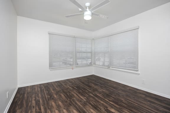 an empty living room with wood flooring and a ceiling fan