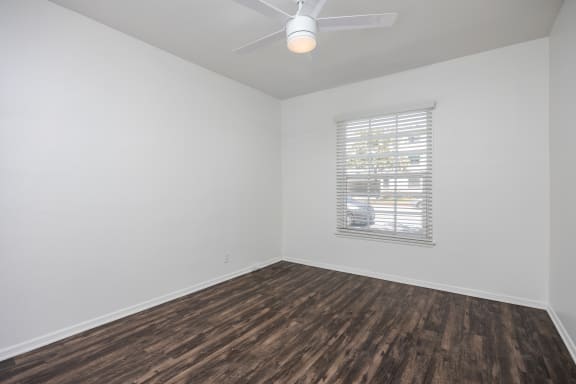 an empty room with wood flooring and a window