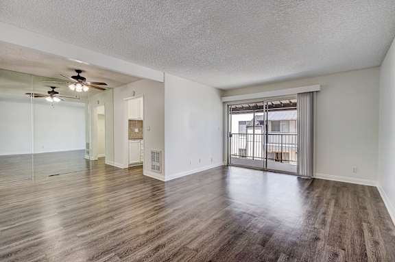 an empty living room with a sliding glass door to a balcony