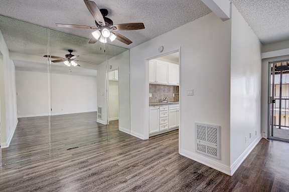 an empty living room and kitchen with a ceiling fan