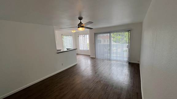 A room with a ceiling fan and sliding glass doors.