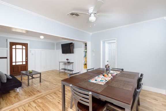 a dining room and living room with a wooden table and a ceiling fan