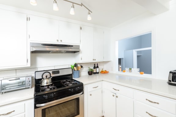 a white kitchen with stainless steel appliances and white cabinets