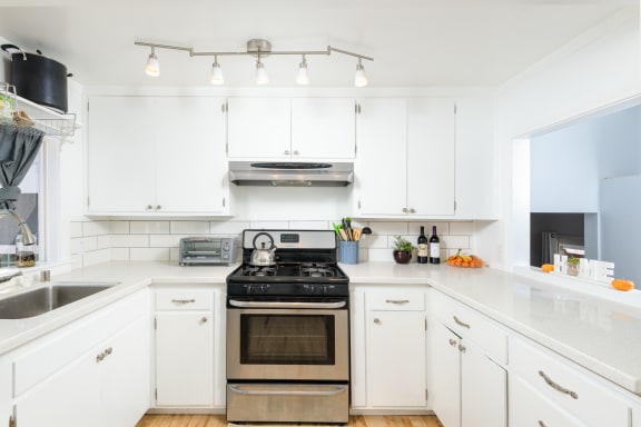 a white kitchen with stainless steel appliances and white cabinets