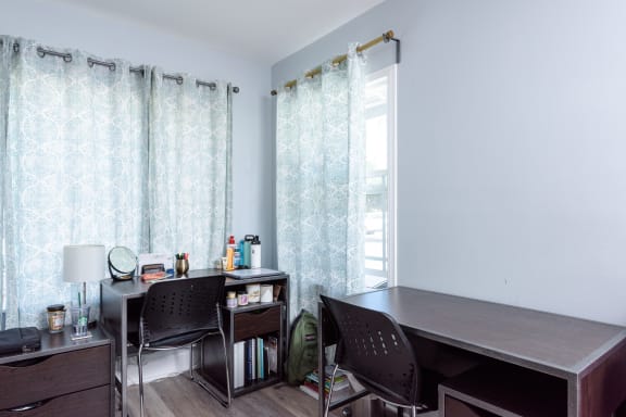 a home office with a desk and a window with curtains