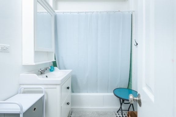 a white bathroom with a shower curtain and a sink
