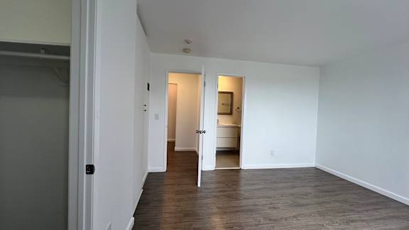 A room with white walls and wooden flooring with two doors.