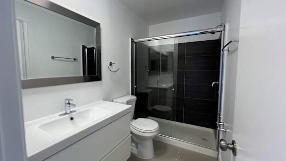A white bathroom with a toilet, sink, and shower.