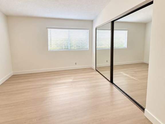 A room with wooden flooring and a large mirror on the wall.