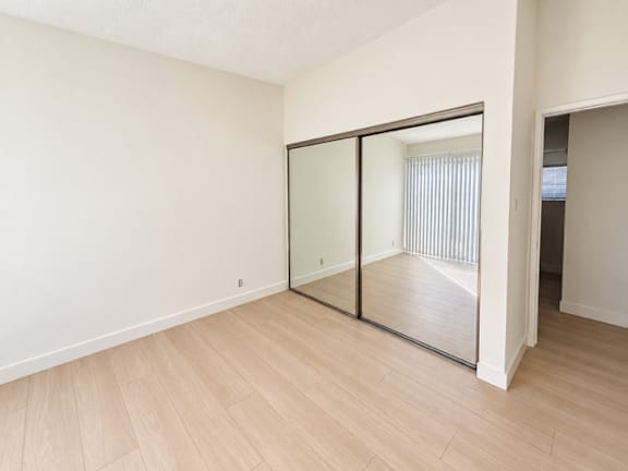 A room with a sliding glass door and wooden flooring.