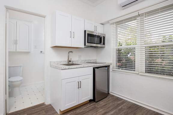 A kitchen with white cabinets and a marble countertop.