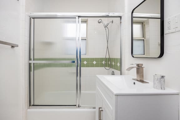 A white bathroom with a glass shower door and a white sink.