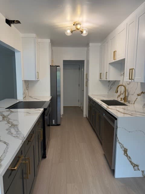 A kitchen with white cabinets and marble countertops.