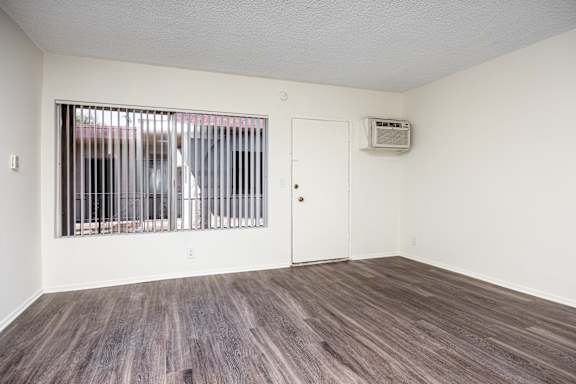 the living room of an apartment with a large window and wood flooring