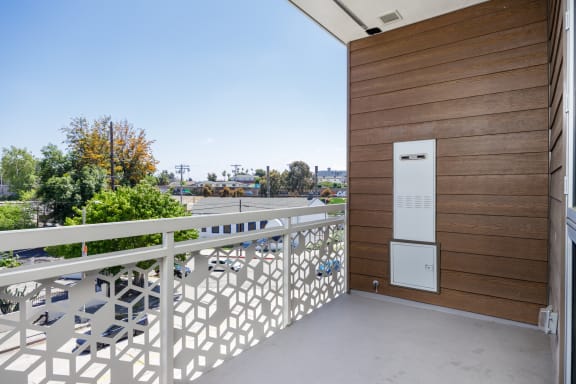 a balcony with a white railing and a wooden wall and a parking lot