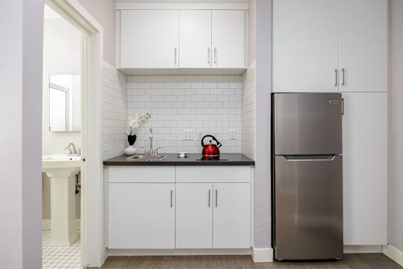 a kitchen with white cabinets and a stainless steel refrigerator
