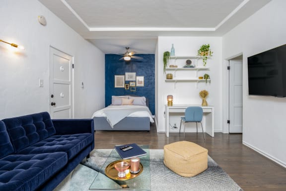 a living room with a blue couch and a bed