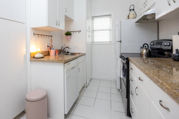 a kitchen with white cabinets and counters and a white refrigerator