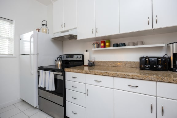 a kitchen with white cabinets and a counter top and a refrigerator