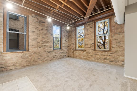 an empty living room with brick walls and a window