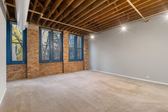 an empty room with a brick wall and blue windows