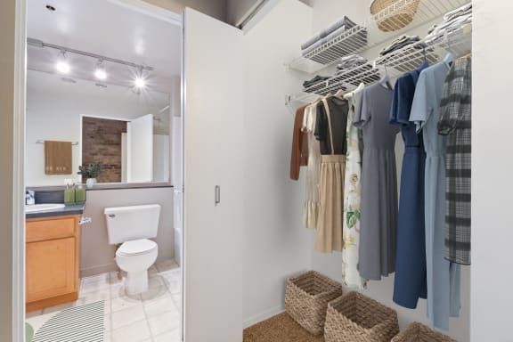 a bathroom with a shower and a closet with clothes and a toilet