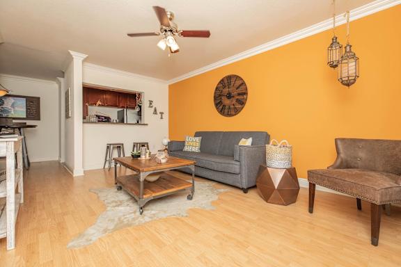 A living room with a grey couch, a wooden coffee table, and a rug on the floor. at The Cove at State Street Apartments, Baton Rouge, Louisiana
