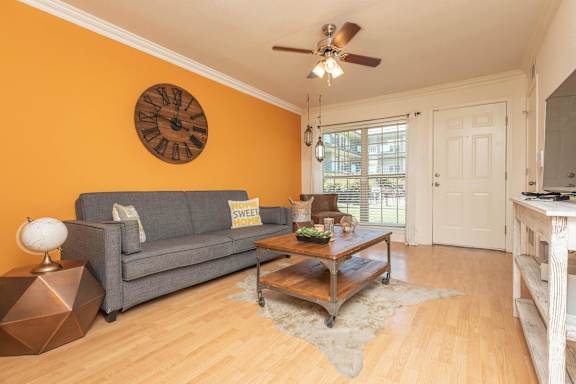 A living room with a grey couch, a wooden coffee table, and a ceiling fan. at The Cove at State Street Apartments, Louisiana, 70802