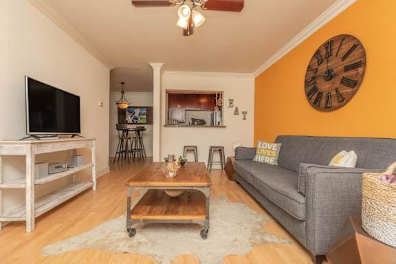 A living room with a grey couch, a wooden coffee table, and a flat screen TV. at The Cove at State Street Apartments, Baton Rouge, LA