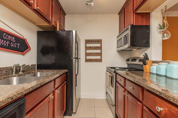 A kitchen with a black fridge and wooden cabinets. at The Cove at State Street Apartments, Baton Rouge, LA