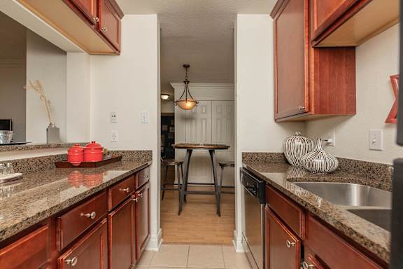 A kitchen with brown cabinets and a granite counter top. at The Cove at State Street Apartments, Baton Rouge, LA, 70802