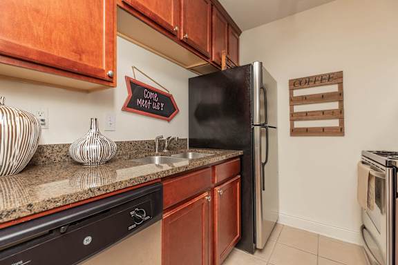 A kitchen with a black fridge and wooden cabinets. at The Cove at State Street Apartments, Louisiana, 70802