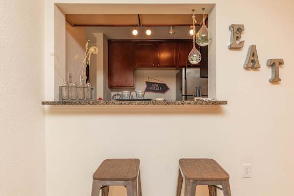 A kitchen with a counter and two stools. at The Cove at State Street Apartments, Baton Rouge