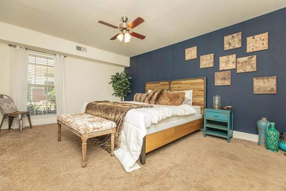 A bedroom with a bed, a chair, and a potted plant. at The Cove at State Street Apartments, Baton Rouge, Louisiana