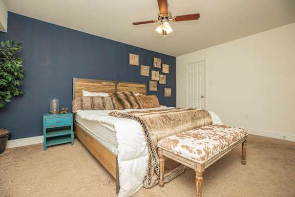 A bedroom with a bed, a bench, and a ceiling fan. at The Cove at State Street Apartments, Louisiana, 70802